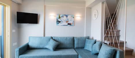 Una sala de estar moderna con un sofá seccional azul, un televisor de pantalla plana y un adorno en la pared.