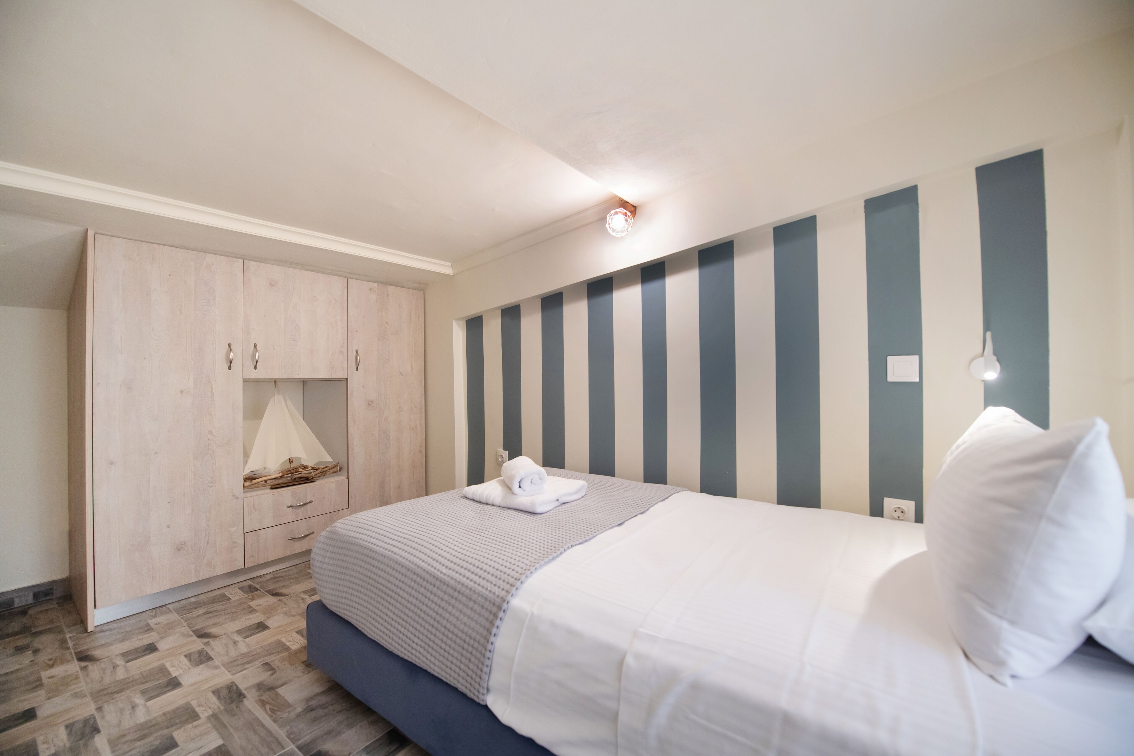 A bedroom with a bed, a wardrobe, and a wall-mounted light fixture.