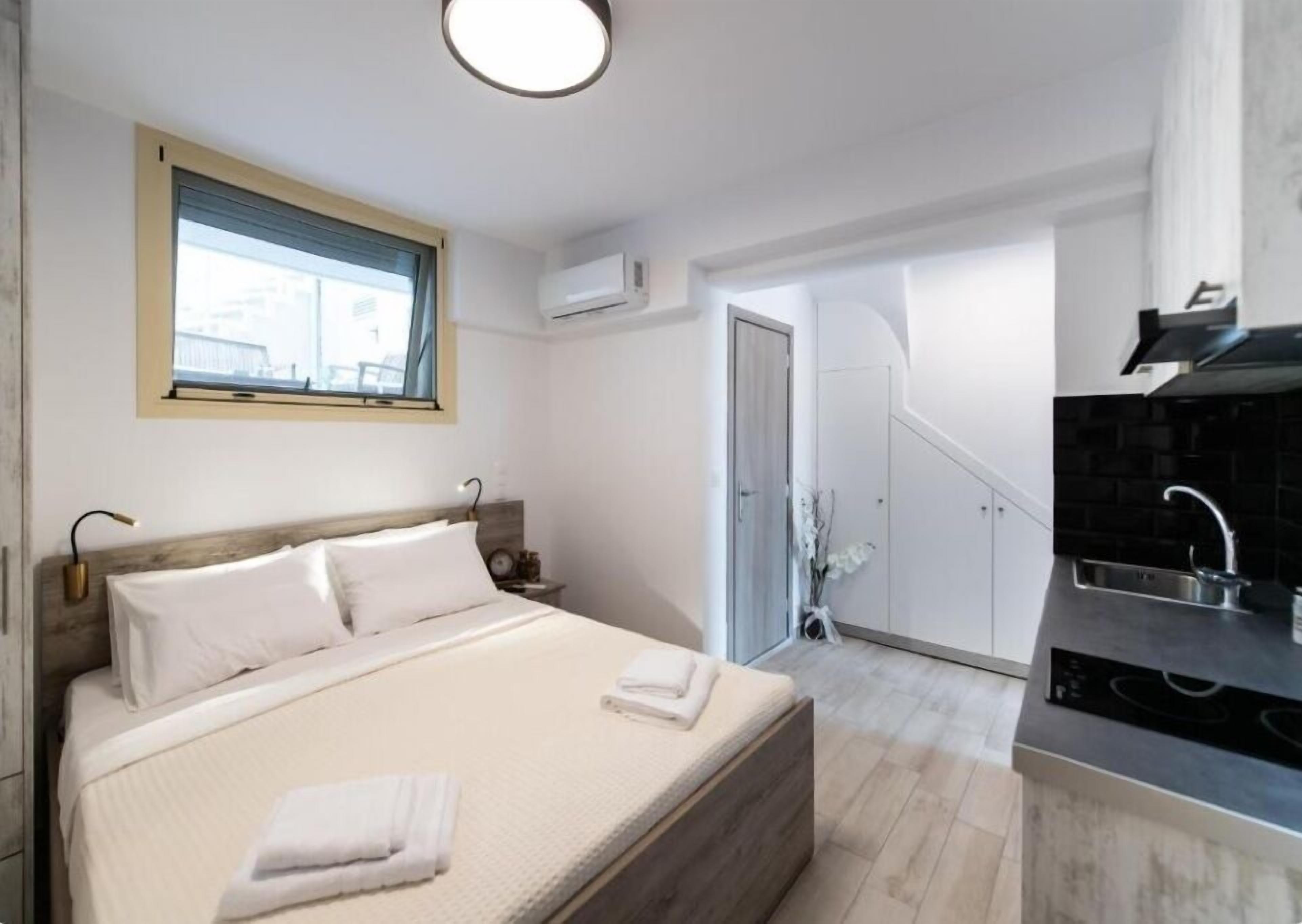 Ein Schlafzimmer mit Bett, Nachttischen, einem Fenster und Blick auf die Stadt.
