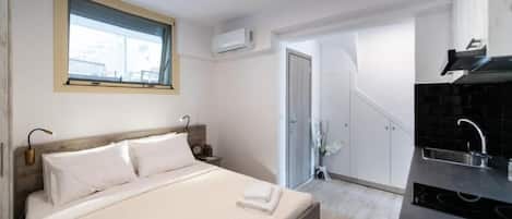 Quarto com cama, mesas de cabeceira, janela e vista da cidade.