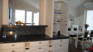 A kitchen with a granite countertop, white cabinetry, and a dining area with a white table and chairs.