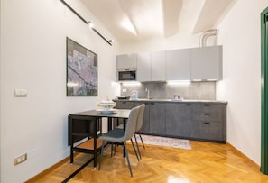 Une cuisine moderne avec des meubles de rangement gris, une table à manger noire et une chaise.