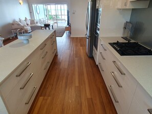 A modern kitchen with a central island, stainless steel appliances, and a view to a balcony. - Kabine Waterfront Lakehouse in Sunshine (Sunshine)