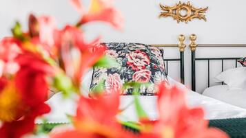 A bed with a floral pillow, a gold decorative wall piece, and a white headboard.