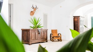 A room with a wooden cabinet, a wicker chair, a mounted animal head, and a potted plant. - Eighteen21 Houses - Casa dos Condes (Sousel)