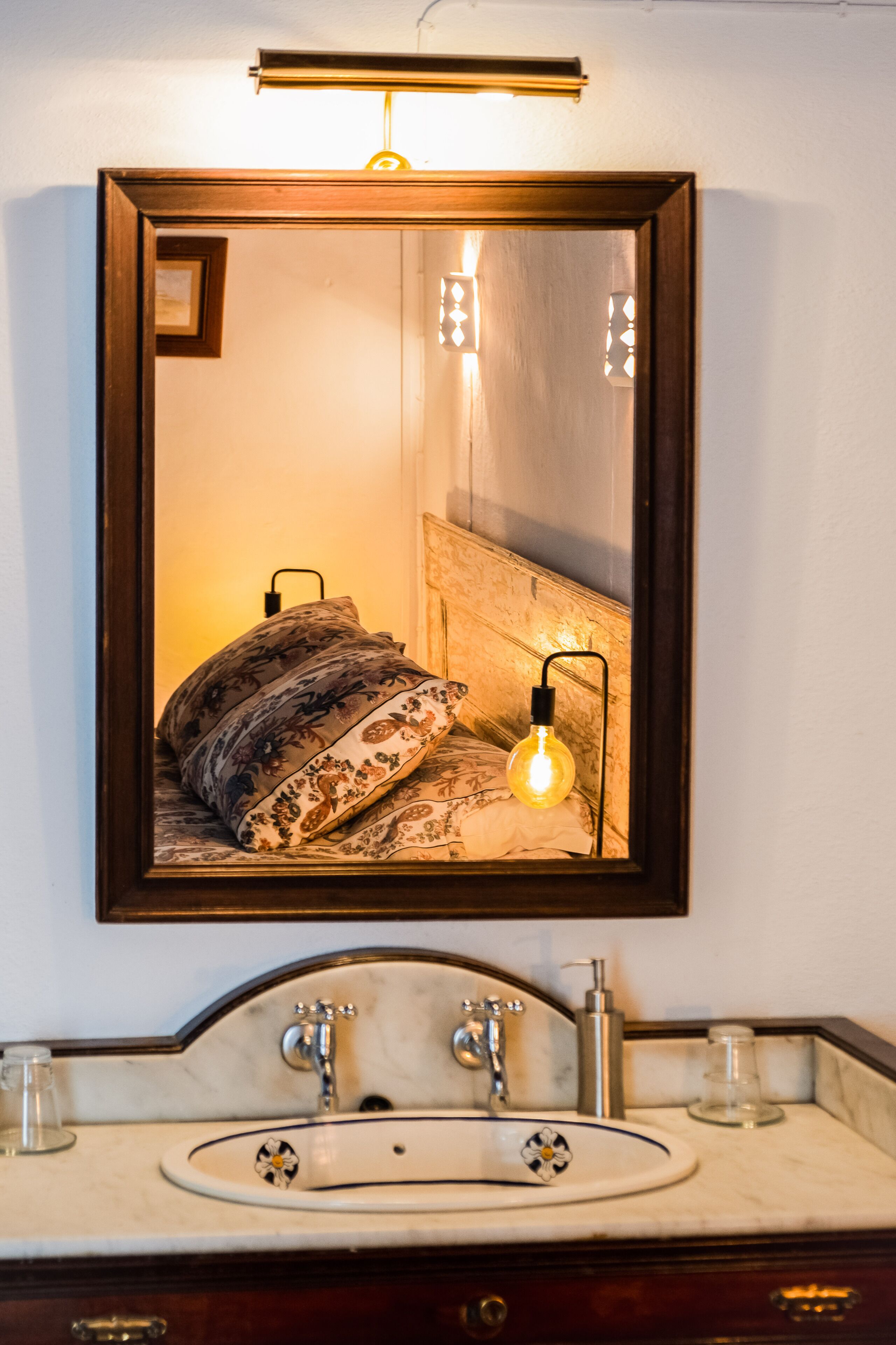 Ein Badezimmer mit Marmorwaschbecken, einem Spiegel und einer Nachttischlampe.