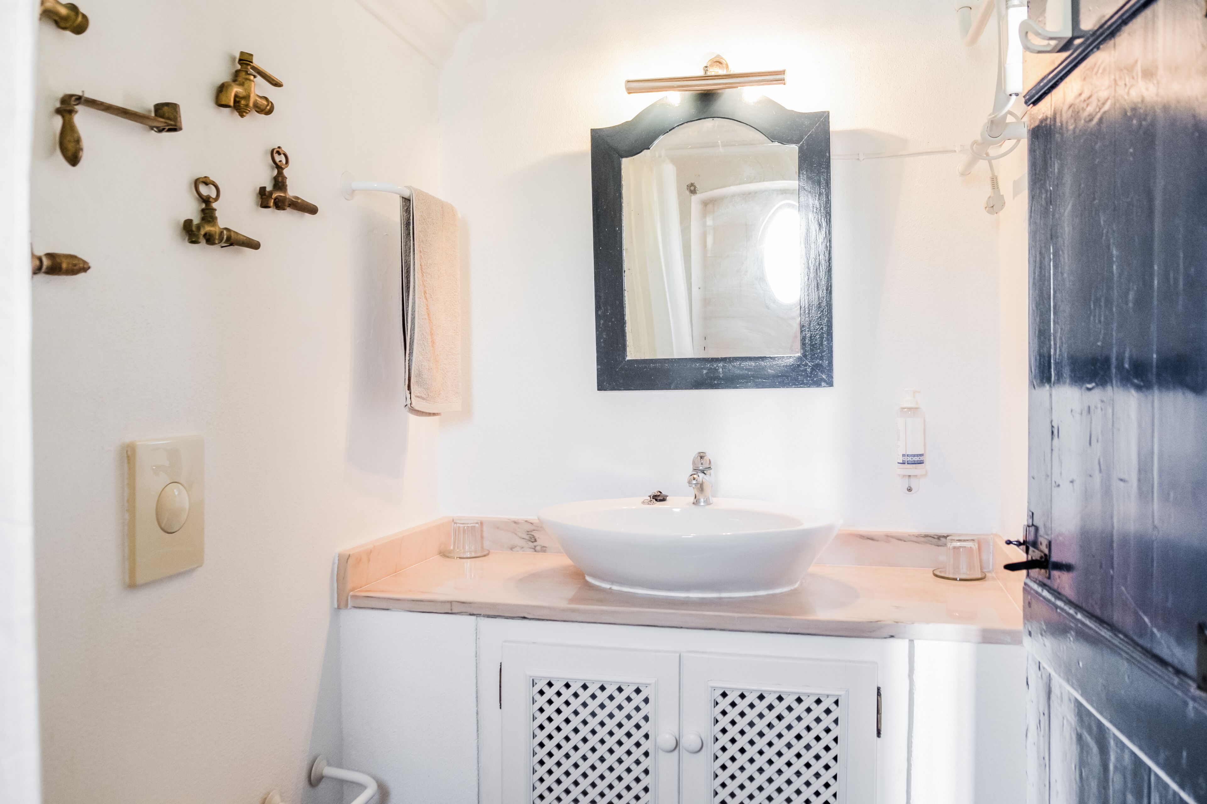 Un baño con un lavamanos blanco, un espejo y una lámpara de pared.