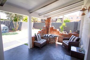 An outdoor patio with a brick fireplace, wicker furniture, and a covered ceiling.