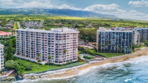 A coastal hotel with multiple high-rise buildings, a beachfront, and a view of distant mountains.