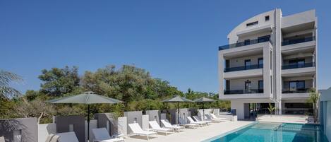 En säsongsöppen utomhuspool, parasoller och solstolar