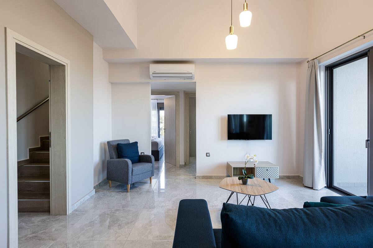 A modern living room with a sofa, a coffee table, and a TV mounted on the wall.