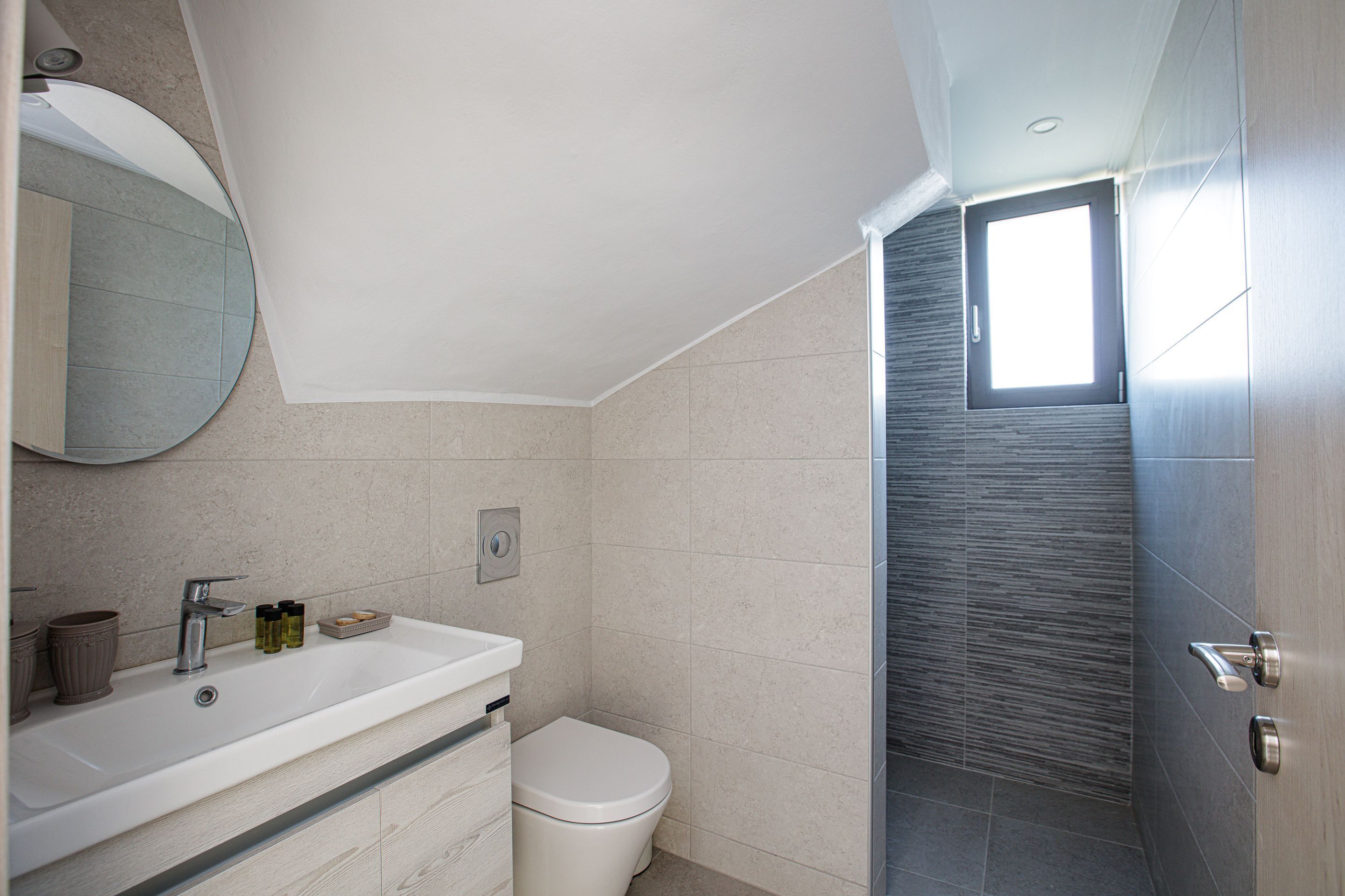 A modern bathroom with a white sink, mirror, and toilet.