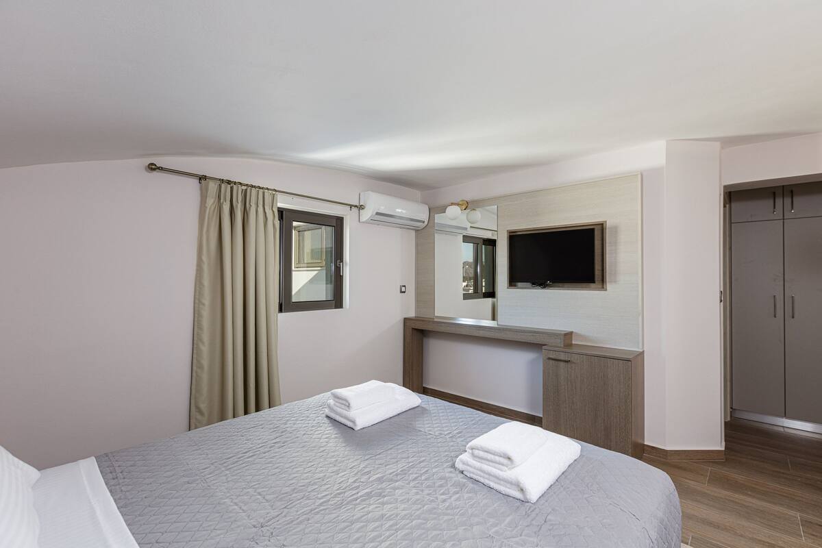 A hotel room with a bed, a bathroom, a mirror, and a wardrobe.