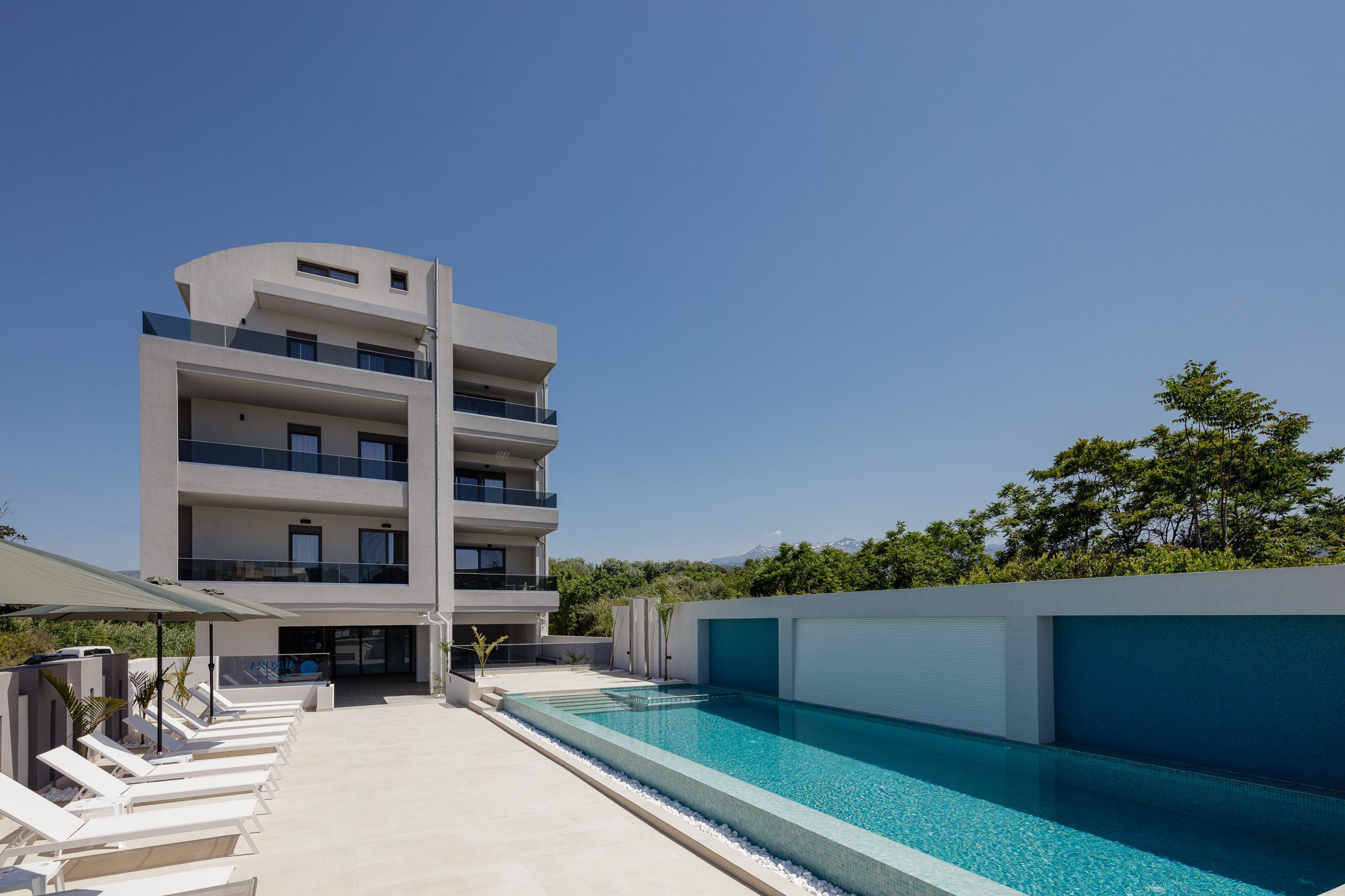 Ein modernes, mehrstöckiges Gebäude mit Pool, Außenbereich und freiem Blick auf die umliegende Landschaft.