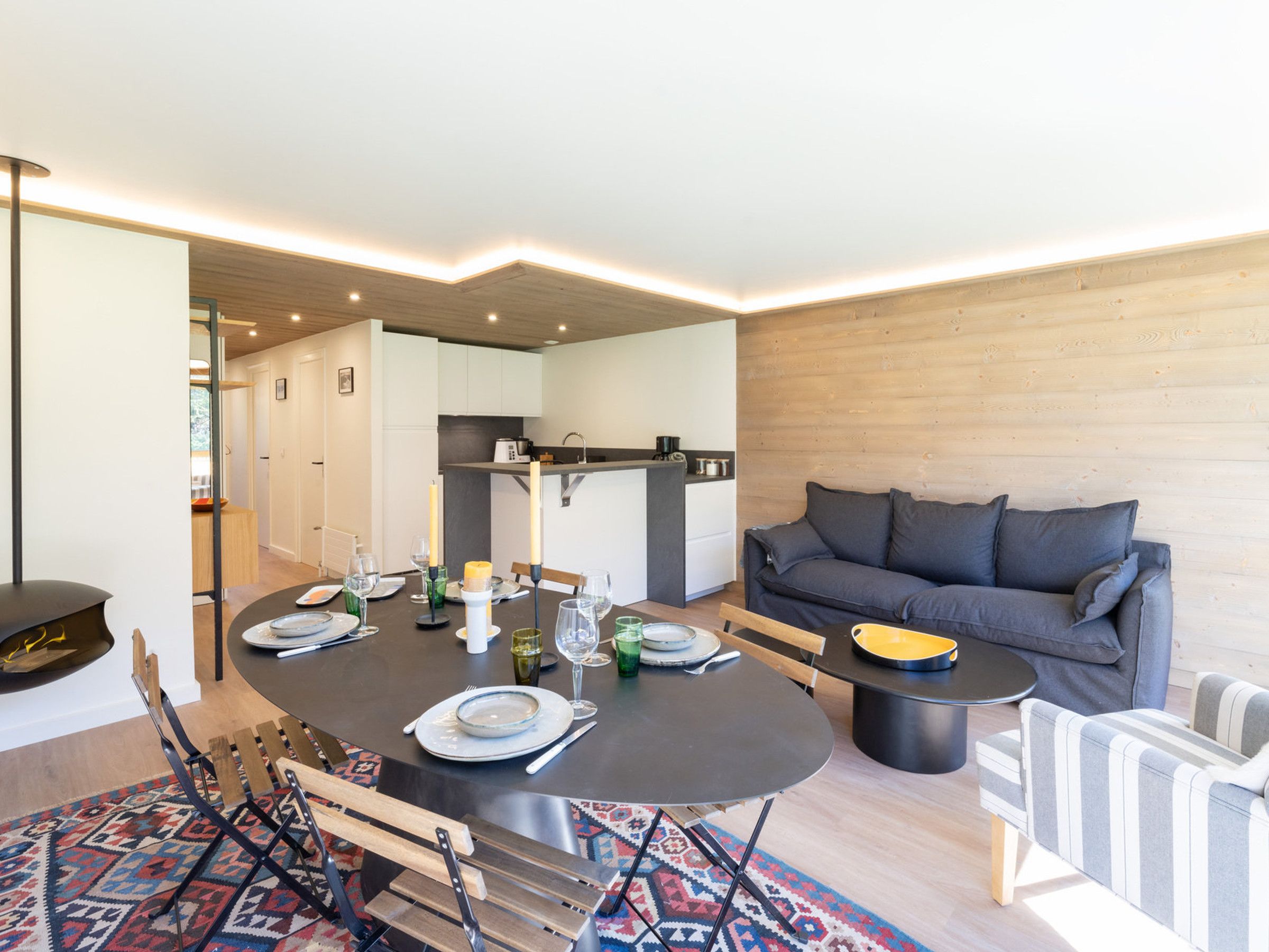 A modern living room with a dining table set for four, a sofa, and a small side table.