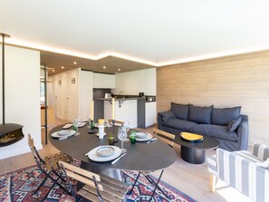 A modern living room with a dining table set for four, a sofa, and a small side table.