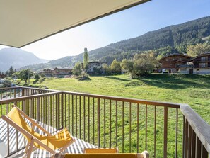 A balcony with a view of a green field and houses in the background.