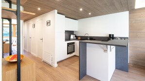 A modern kitchen with white cabinetry, a built-in oven, and a grey countertop. - Renovated apartment near slopes with Wi-Fi for families (Courchevel)