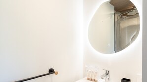 A bathroom with a round mirror, a white sink, and a black towel rack. - Renovated apartment near slopes with Wi-Fi for families (Courchevel)