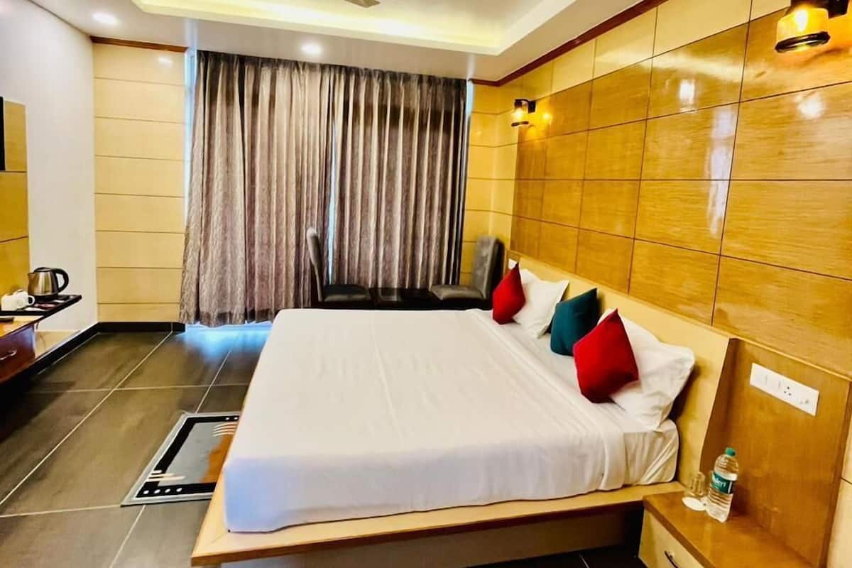 A hotel room with a large bed, a wooden headboard, a ceiling fan, and a view of the outside through a window with curtains.