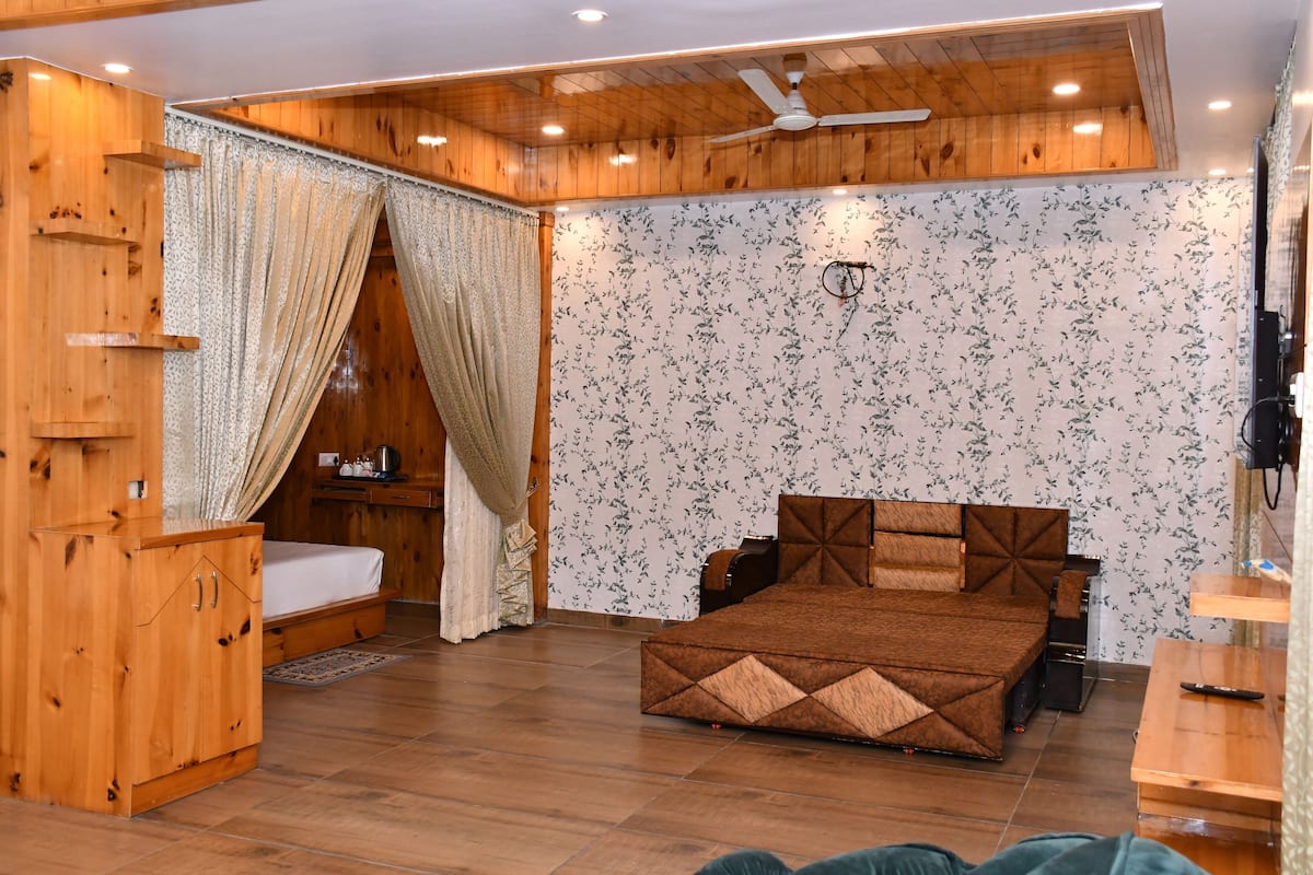 A wooden room with a bed, a wardrobe, a ceiling fan, and a wall with floral wallpaper.