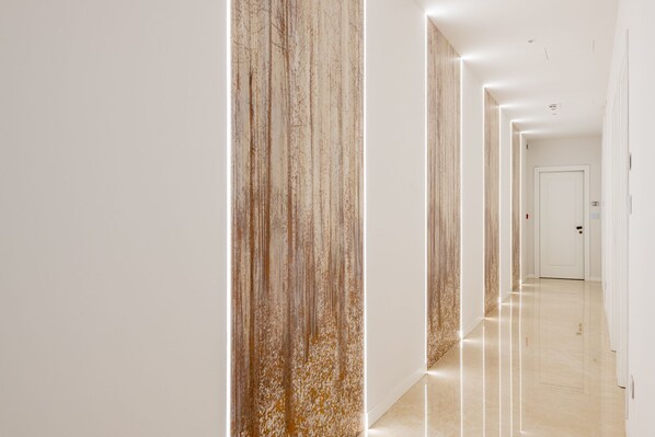 A modern hallway with a glossy floor and vertical wooden panels. - PETIT HOTEL (Prato)