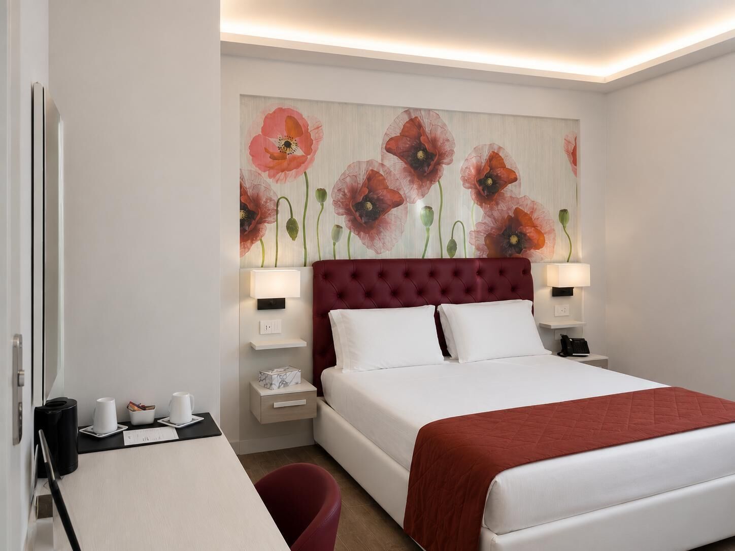 A hotel room with a large bed, a desk, and a wall with a floral painting.