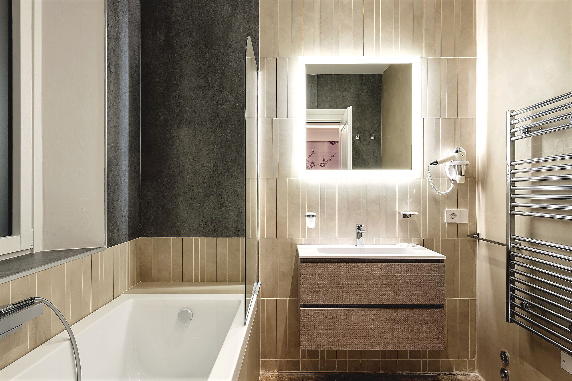 A modern bathroom with a bathtub, a sink, a mirror, and a towel rack.