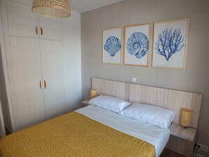 Une chambre à coucher avec un lit, une armoire et trois œuvres d’art encadrées accrochées au mur.