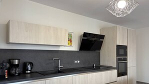 A modern kitchen with a black countertop, stainless steel appliances, and light wood cabinetry. - Peaceful Mountain Escape: 2BR Apartment, Terrace, Close to Ski, Free Parking, WiFi (Villard-de-Lans)