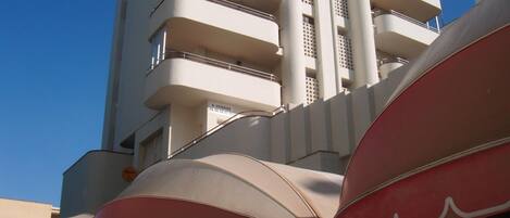 A high-rise building with multiple balconies and a clear blue sky.