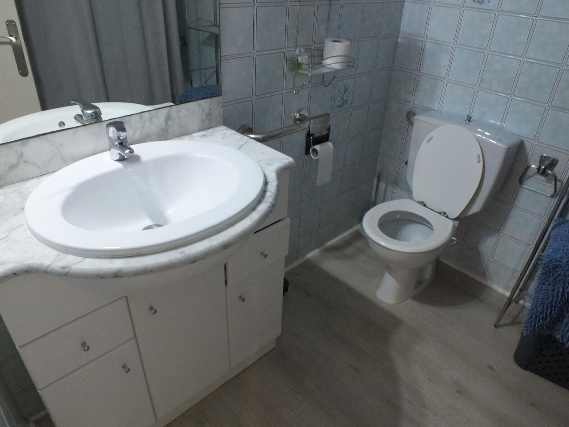 Un baño con lavamanos blanco, inodoro y paredes con azulejos.