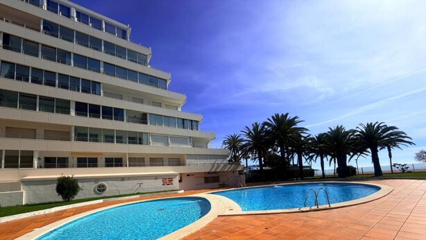 Un hôtel moderne doté d’une piscine, de palmiers et offrant une vue sur un ciel bleu azur.