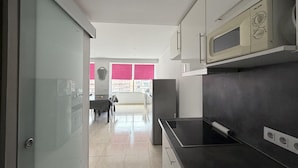 A modern kitchen with a black countertop, a microwave, and a stove. - Charming 1-bedroom apartment with pool & garden in Roses Santa-Margarita (Roses)