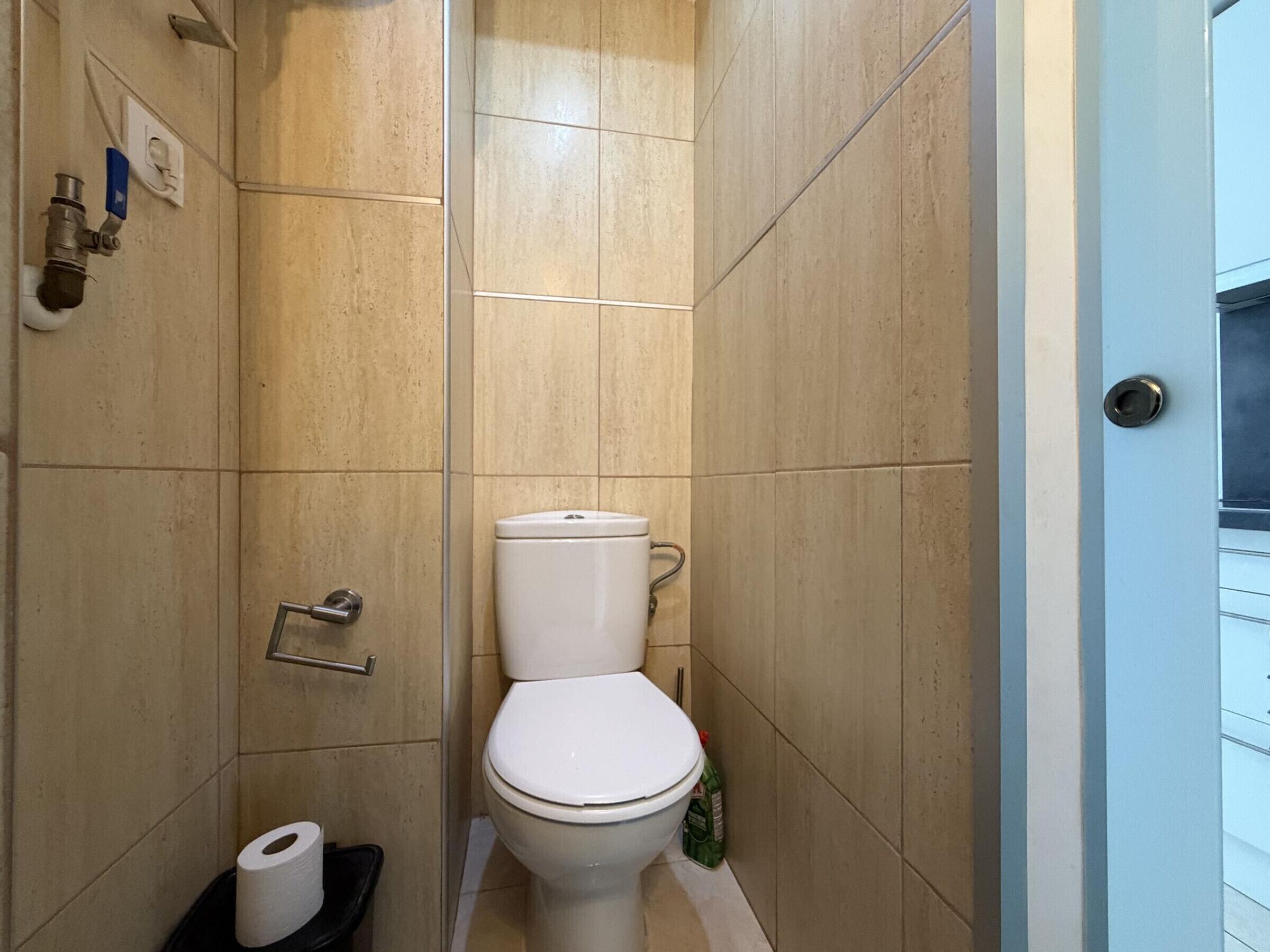 A small, tiled bathroom with a toilet, a hand dryer, and a paper towel dispenser.