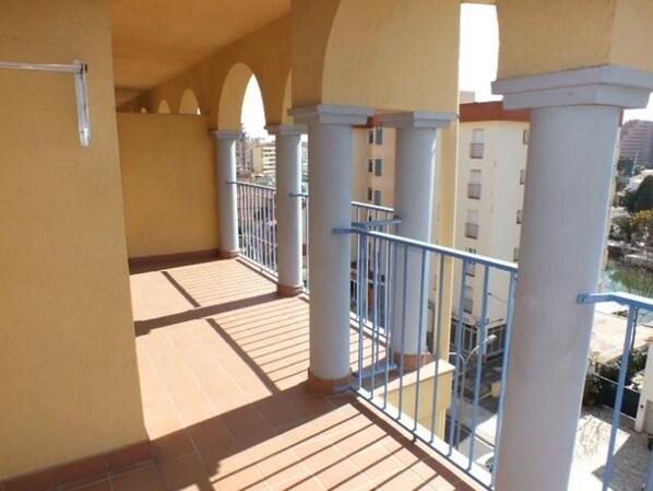 A balcony with tiled flooring, white columns, and blue railings. - Apartment in Roses for 6 with pool and parking (Roses)