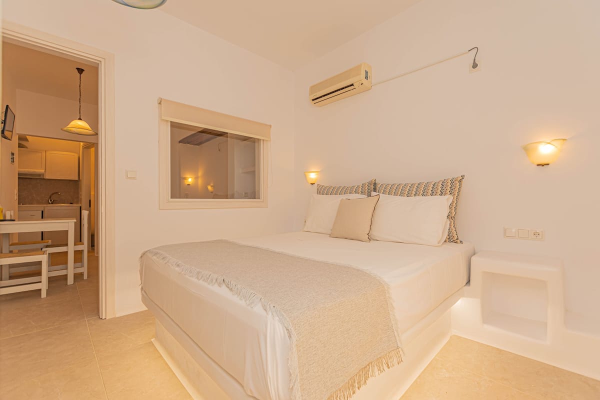 Un dormitorio con cama, mesita de noche y ventana.