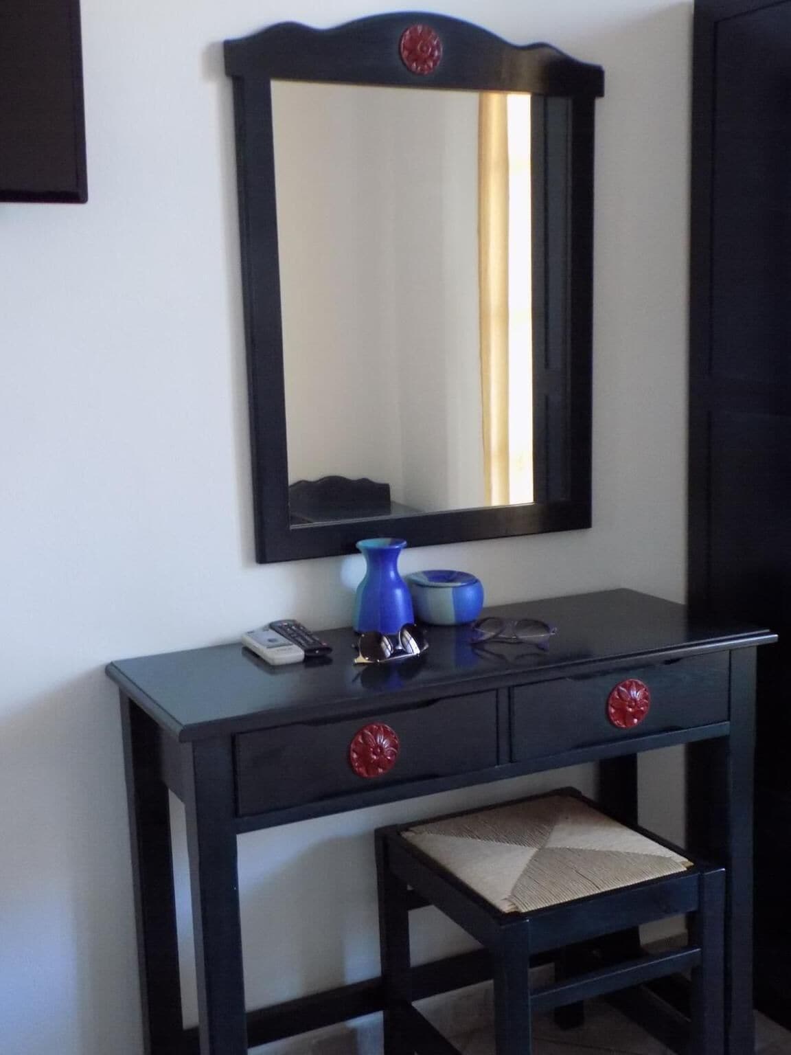A dark wooden vanity with a mirror, two drawers, and a small stool.