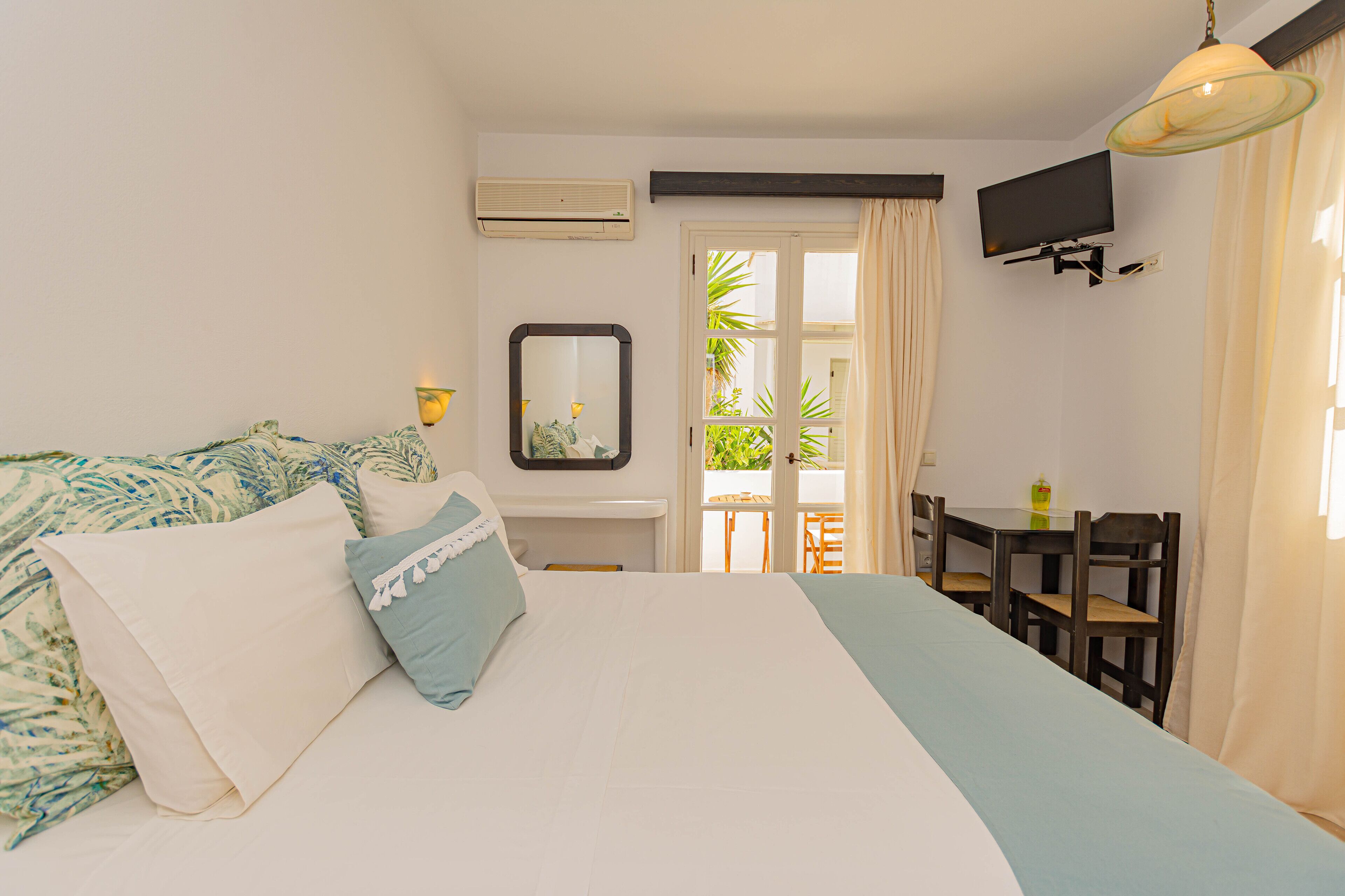 A bedroom with a bed, a TV, a table, and chairs.