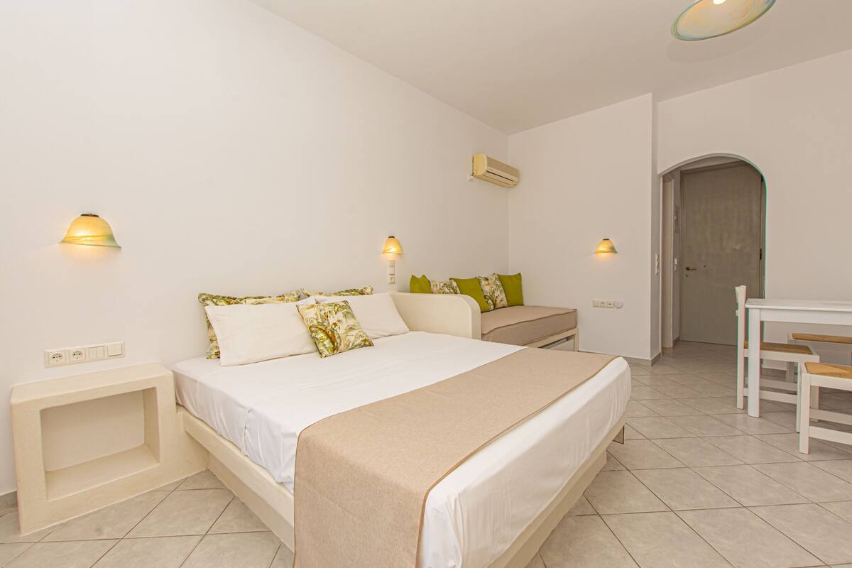 Un dormitorio con cama, mesitas de noche, un escritorio y un arco de entrada.