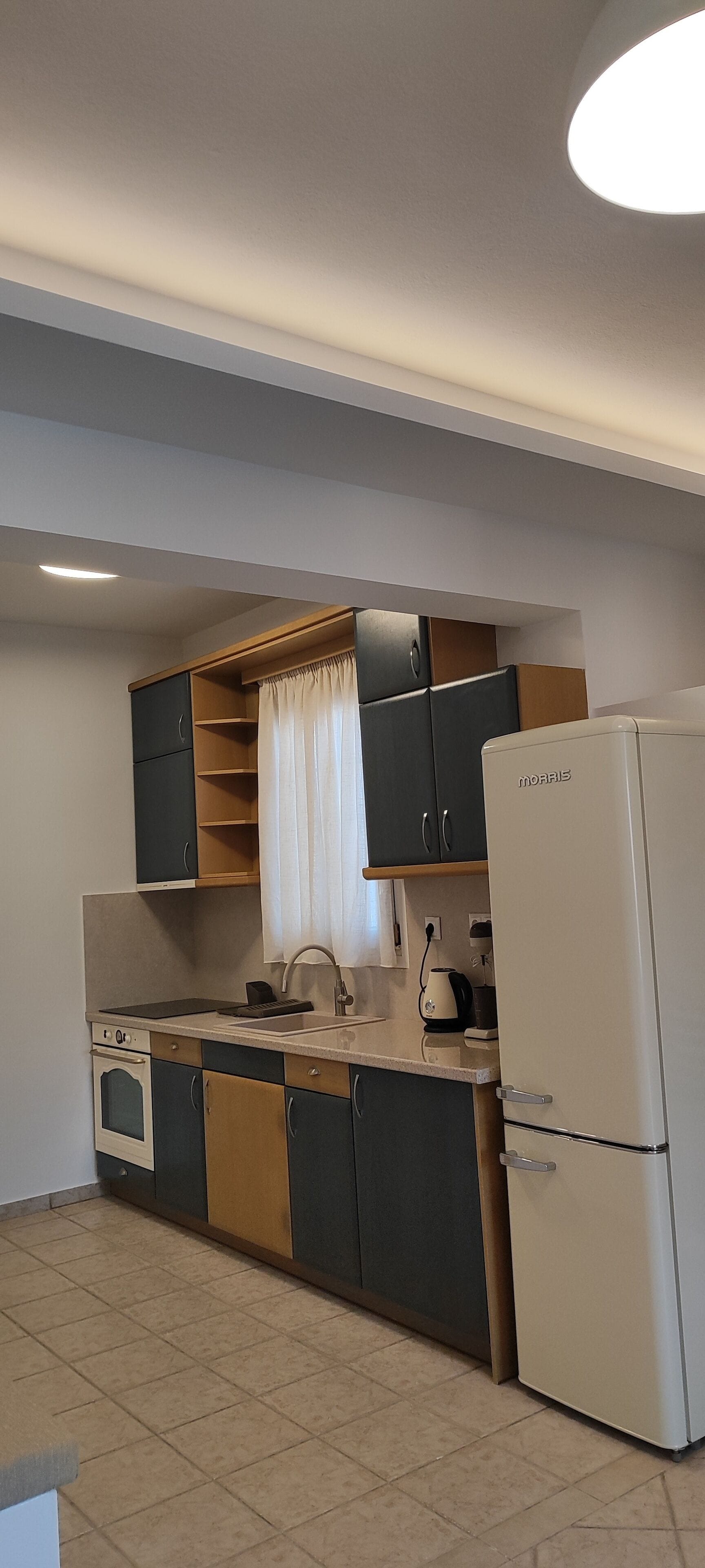 Cocina pequeña con refrigerador, estufa y armarios.