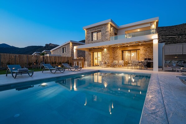 Relax by the outdoor pool with lounge chairs, or enjoy a meal in the outdoor dining area, surrounded by a scenic mountain view.