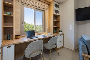 Work in comfort with a desk, chairs, and a TV, plus a view of lush greenery outside.