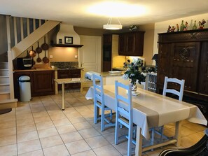 A kitchen with a dining table, chairs, a trash can, and a staircase. - Character house for 4 people (Brennilis)