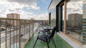 Un balcón con vistas a un paisaje urbano, una mesa con sillas y una planta en maceta.