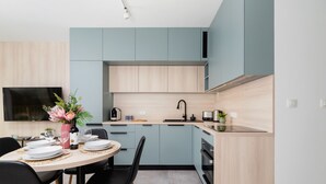Una cocina moderna con armarios azul claro, un comedor con una mesa redonda y sillas, y un televisor montado en la pared.