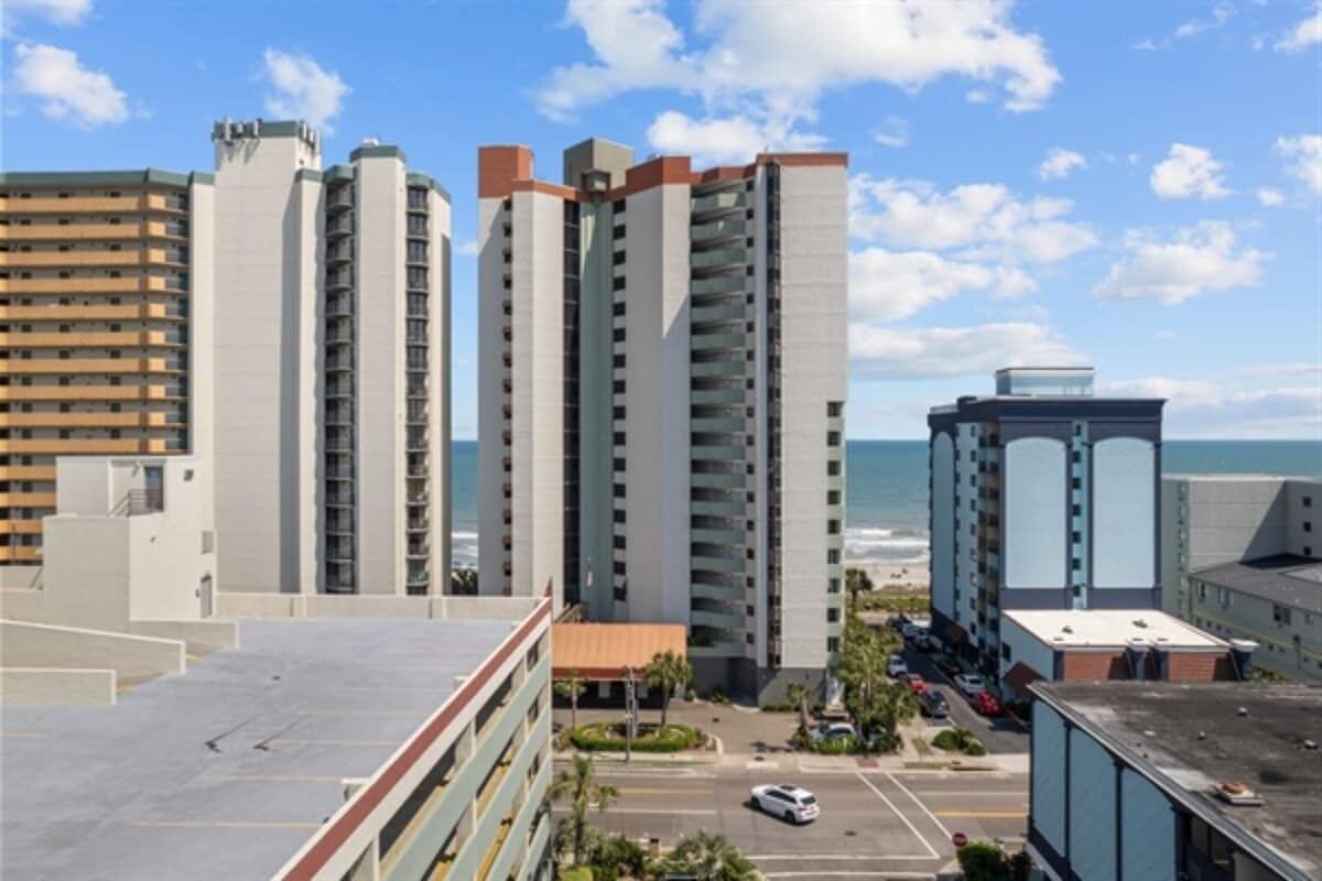 Un grand hôtel à plusieurs étages, doté d’un parking et offrant une vue sur l’océan.