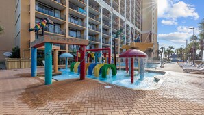 A hotel with a water play area, palm trees, and a poolside lounge. - New, Caravelle Resort, Amazing Oceanview, Updated! (Myrtle Beach)