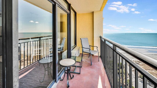 A balcony with a view of the ocean, a table, and two chairs. - New, Caravelle Resort, Amazing Oceanview, Updated! (Myrtle Beach)
