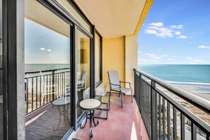 A balcony with a view of the ocean, a table, and two chairs. - New, Caravelle Resort, Amazing Oceanview, Updated! (Myrtle Beach)